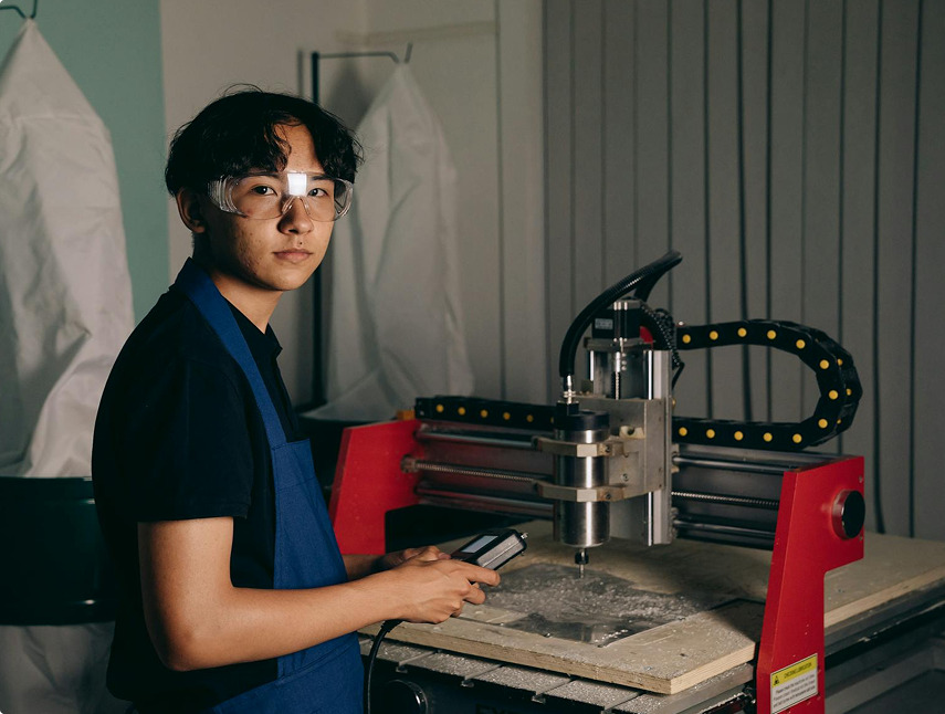 Человек в очках и фартуке работает с фрезерным станком